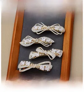 Close-up of four elegant bow hair clips with pearls, rhinestones, and lilac flowers