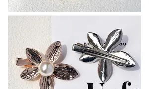 Detail of flower hair clips with metallic texture and white pearl on alligator clip