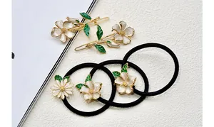 Detail of floral hair clips and ties with white enamel petals and golden alloy frame