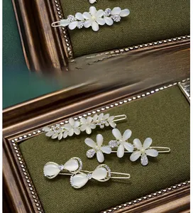 Close-up of golden hair clips with creamy cat-eye stones and crystal butterfly detail