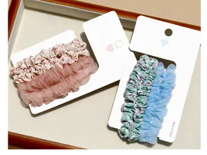 Detail of floral and mesh scrunchie sets on heart cutout cards over a wooden tray