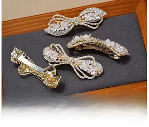 Detail of elegant gold hair clips featuring sparkling rhinestones and delicate white pearls