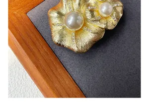 Macro shot of vintage gold flower brooch with large pearls and crystal details