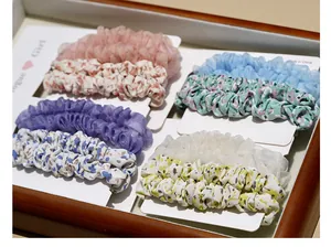 Close-up of floral and mesh fabric scrunchies set in pastel colors on wooden tray