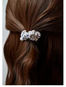 Close-up of floral fabric scrunchie with blue pattern worn on wavy brown hair