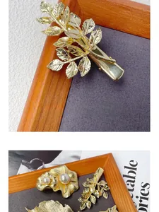 Detail of golden leaf hair clip and floral hairpin with pearls and rhinestones on wood