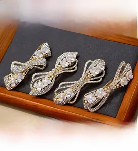 Detail of bow-shaped hair clips with rhinestones and pearls on a grey fabric tray