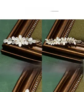 Detail of floral cat eye stone hair clips with sparkling rhinestones and gold leaf branch design