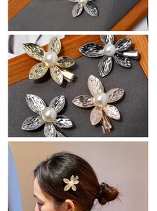 Detail of floral hair clip with hammered metal texture and white pearl center on an alligator clip