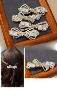 Detailed view of elegant bow hair clips with rhinestones and white pearls on gold alloy