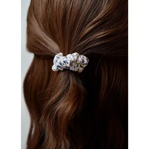 Floral fabric scrunchie with blue and brown patterns shown on long wavy brown hair