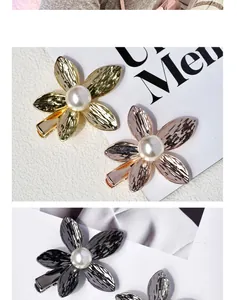 Macro detail of floral hair clip featuring hammered metal petals and pearl center