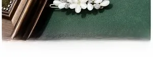 Detail of golden floral hair clip with white cat-eye petals and sparkling rhinestones
