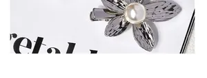 Close-up of a silver flower hair clip with textured petals and a pearl center detail