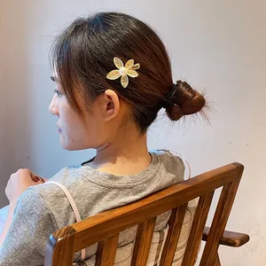 Elegant gold flower hair clip with a white pearl on a woman's side profile hairstyle