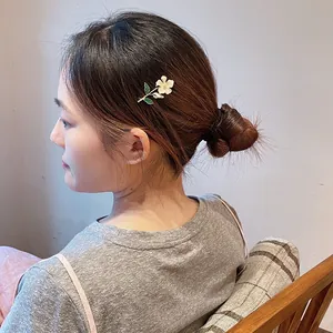 Elegant white flower hair clip accessory worn on a stylish bun for women and girls