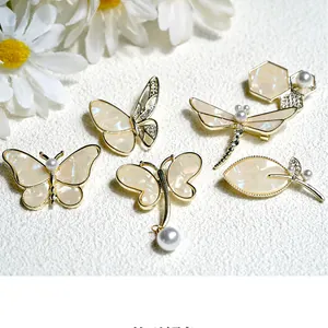 Detailed view of pearl butterfly and dragonfly brooches with gold-tone metal and crystals