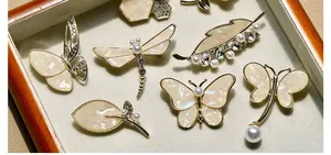 Detailed view of elegant butterfly and dragonfly shell brooches with pearls and crystals