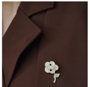 Detail of elegant shell flower brooch with pearl on a dark brown suit jacket lapel