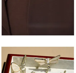 Macro detail of elegant butterfly and dragonfly shell brooches with pearl accents