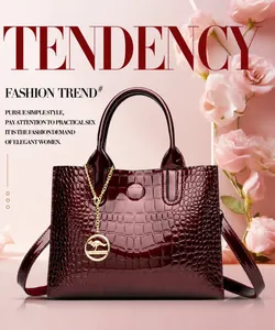 Close-up of wine red patent leather handbag with crocodile pattern and golden pendant