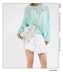 Crossbody white gingerbread man bag with blue bowtie worn by a model in a casual outfit