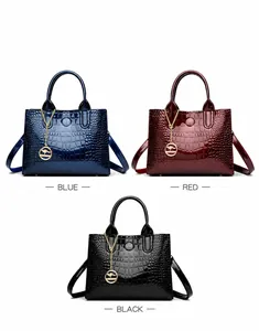 Detail view of glossy crocodile-embossed handbags in blue, burgundy, and black colors