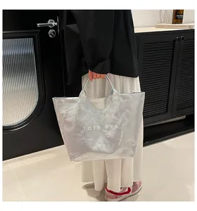 Close-up of a large silver tote bag with crinkled texture and white TOTE BAG lettering