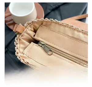 Detail of hand-woven straw saddle bag with vintage bronze zipper and beige fabric lining