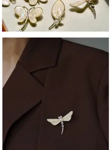 Detail of elegant dragonfly brooch with mother of pearl inlay and white pearls on brown suit