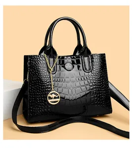 Macro detail of glossy black crocodile pattern texture and golden metal pendant charm