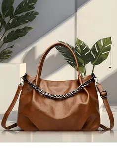 Close-up of large brown tote bag with textured leather and bold metallic chain detail