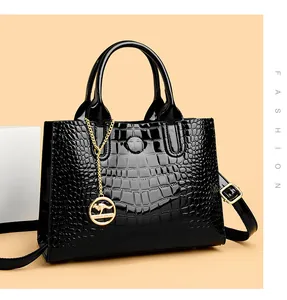 Close-up of black glossy crocodile pattern leather handbag with gold kangaroo charm