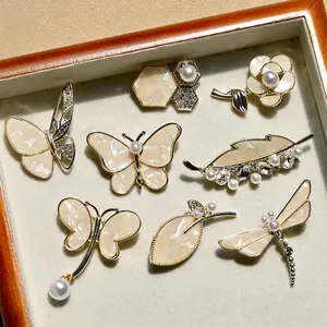 Elegant gold butterfly and pearl brooch set with iridescent shell accents in a tray