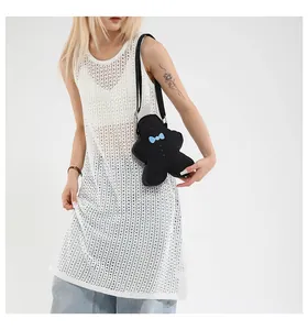 Detail of black gingerbread man crossbody bag with blue bow worn by model on white background