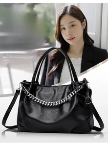 Detail of black tote bag featuring silver chain decor and textured faux leather finish