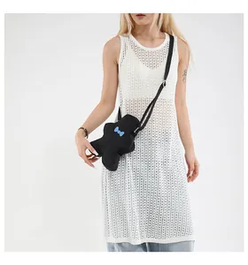 Close-up of ginger-man shaped crossbody bag with blue bow on soft fabric texture