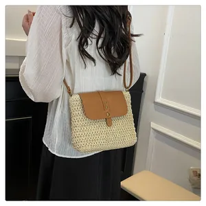 Detail of straw woven crossbody bag with brown leather flap and metallic studs