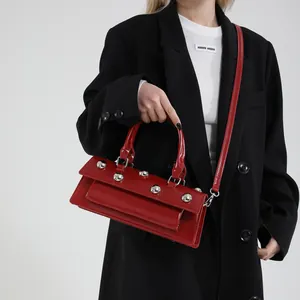 Sac à main chic en cuir rouge avec rivets boules argentés porté par un mannequin