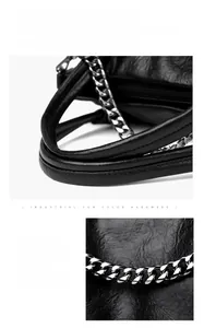 Detail of black leather tote bag featuring sturdy handle and gunmetal chain decoration