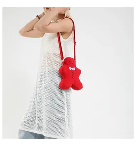 Detailed view of a cute red gingerbread man crossbody bag with a blue bow and strap