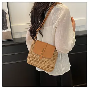 Detail of hand-woven straw crossbody bag with brown leather flap and retro metal buckles