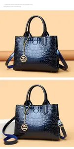 Macro view of blue crocodile pattern patent leather handbag with gold kangaroo charm