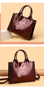 Macro view of burgundy crocodile pattern patent leather tote with kangaroo metal charm