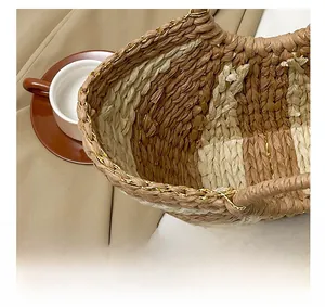 Gros plan sur un sac cabas en paille tissée avec coutures contrastées et chaîne dorée
