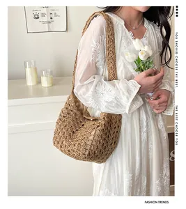 Détail du sac hobo tissé marron à texture ajourée porté par un mannequin en robe