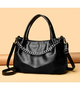 Detail of black tote bag with silver chain, wrinkled faux leather, and top handles