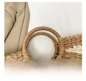 Détail des doubles poignées rondes sur un sac cabas bicolore tissé de fils dorés