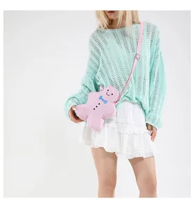 Detail of pink gingerbread man plush shoulder bag with blue bow on a female model