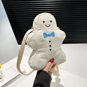 Detail van een crèmewitte crossbodytas in de vorm van een gemberkoekmannetje met blauwe strik